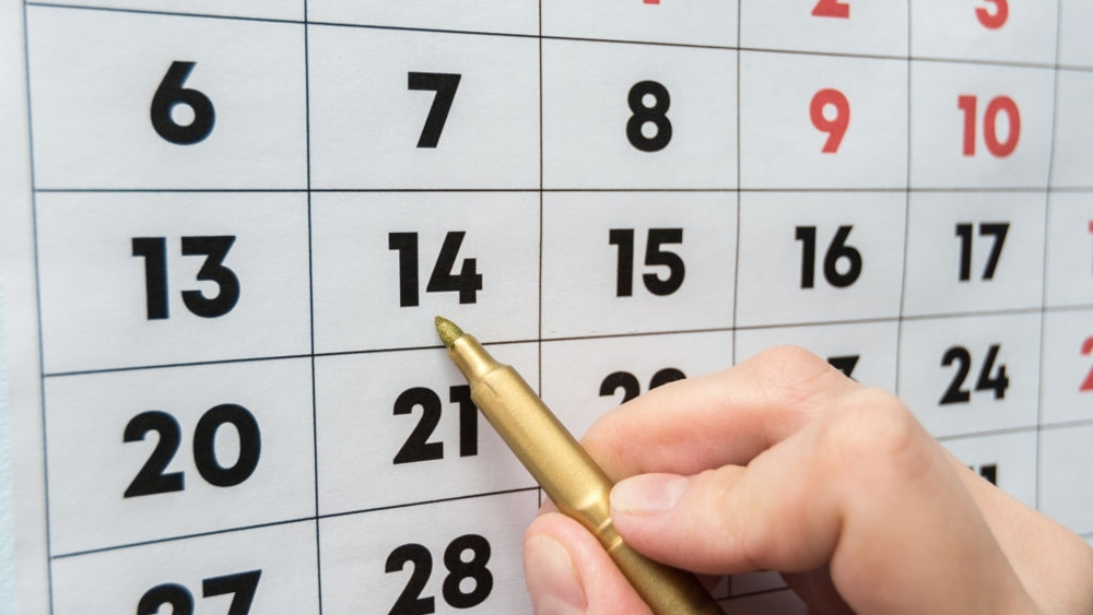 Hand marker indicates the date on the wall calendar
